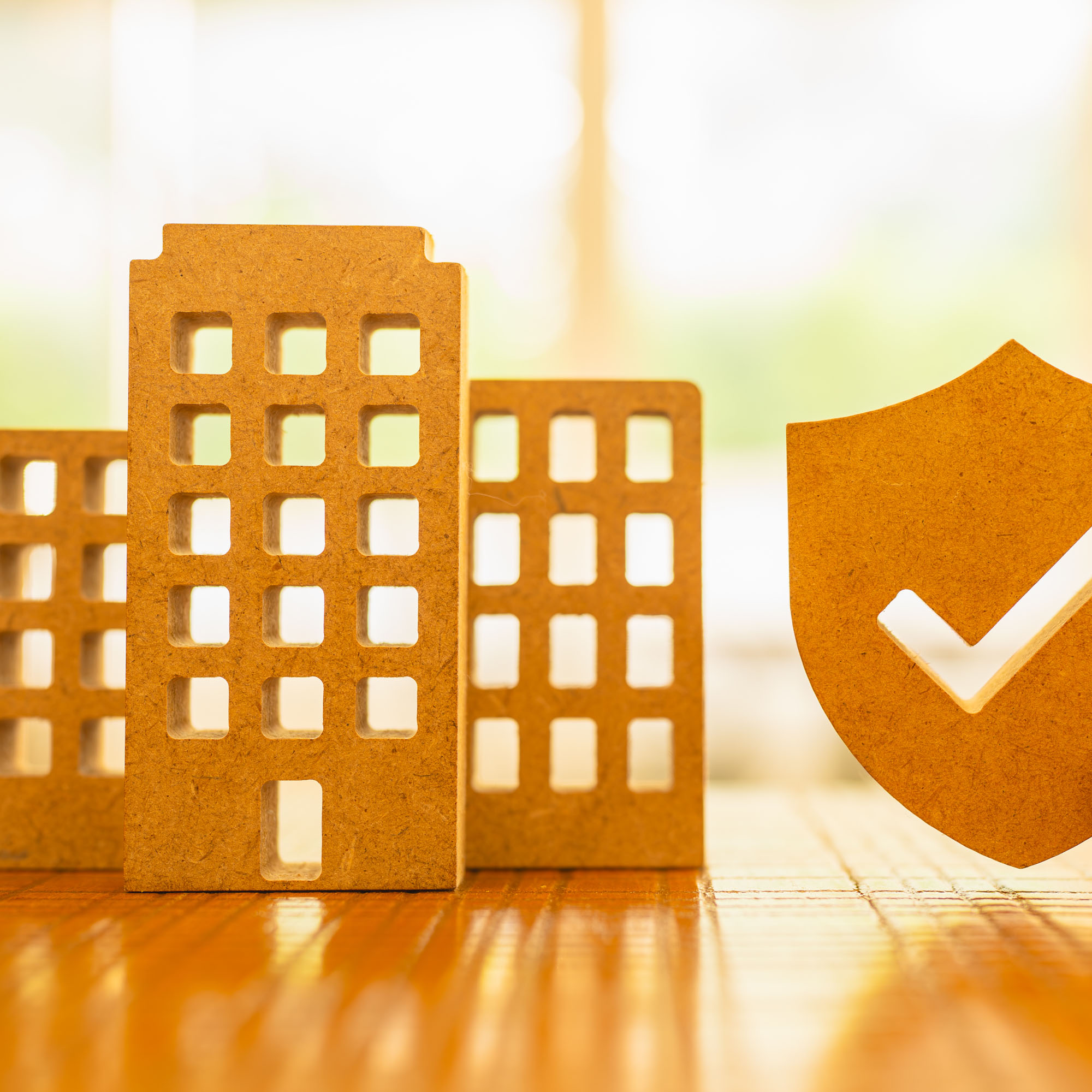 Cutout of commercial buildings beside a shield with a checkmark symbol representing business security and insurance approval